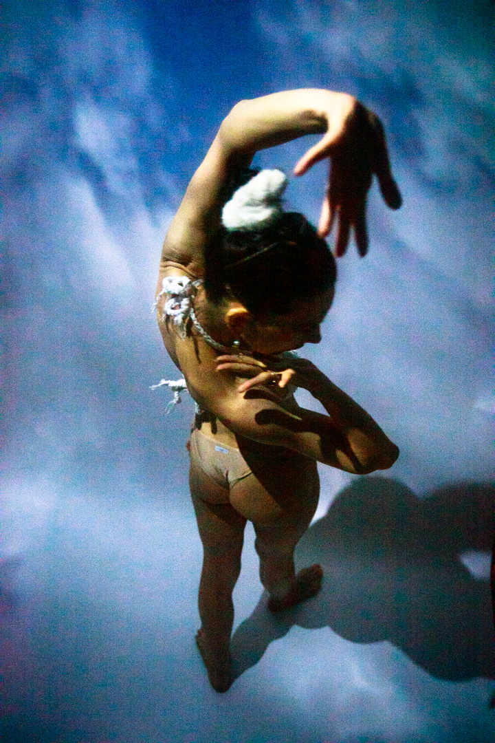 A women in a bikini standing in the sky, with her reaching toward the camera.