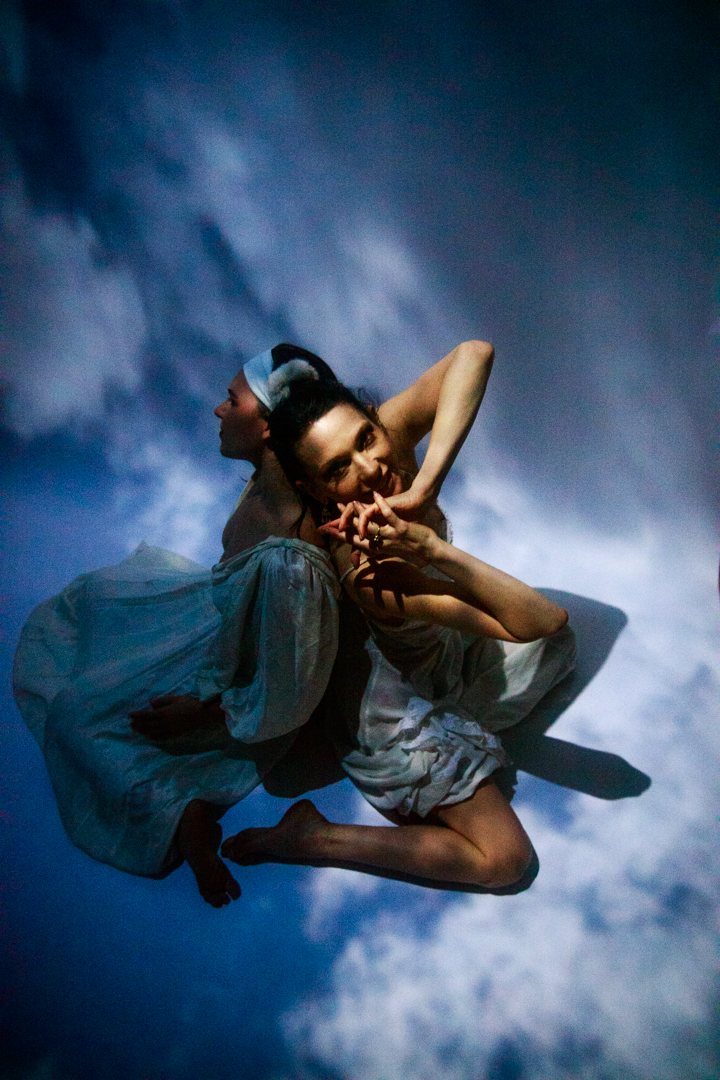 Two women sitting in the sky back to back.